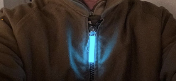 A person wearing a brown jacket and blue light up zipper pull.