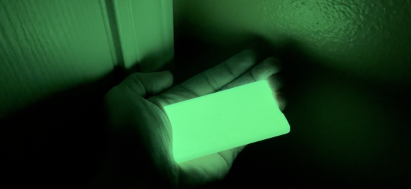 A person holding a glowing paper in their hand.
