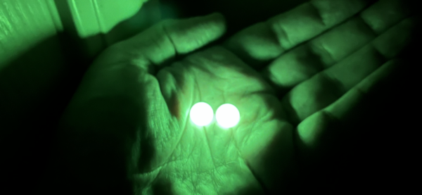 A person 's hand with two green lights in it.