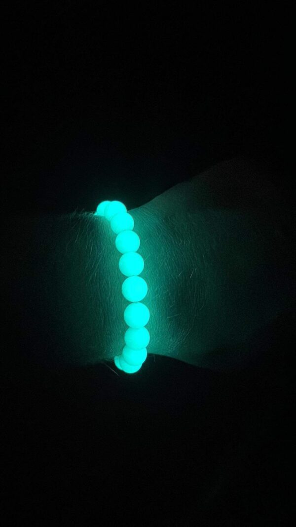 A person wearing a bracelet with glow in the dark beads.