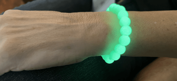 A person wearing a bracelet with green glow in the dark beads.