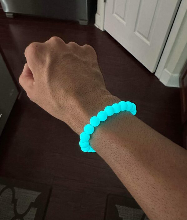A person wearing a bracelet that has glow in the dark beads.